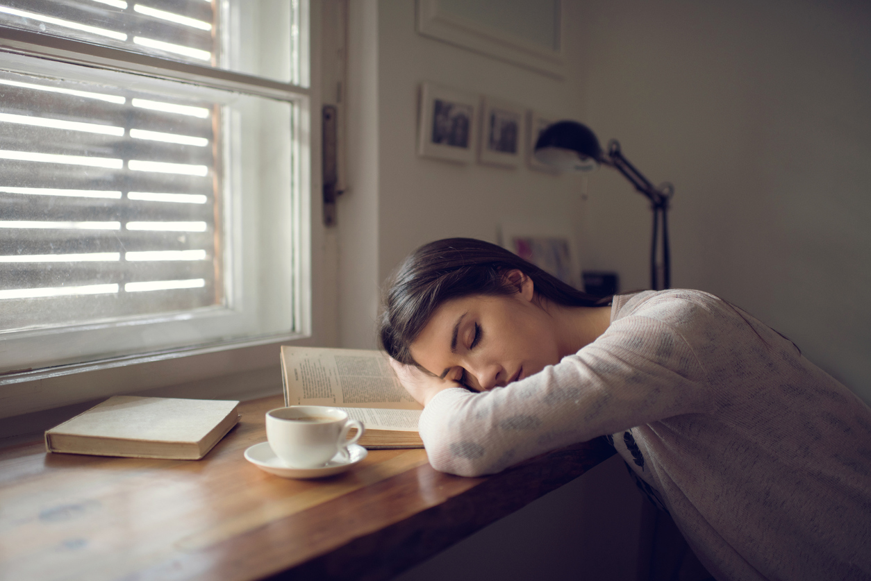 Tired young woman taking a break from learning and napping on the book.